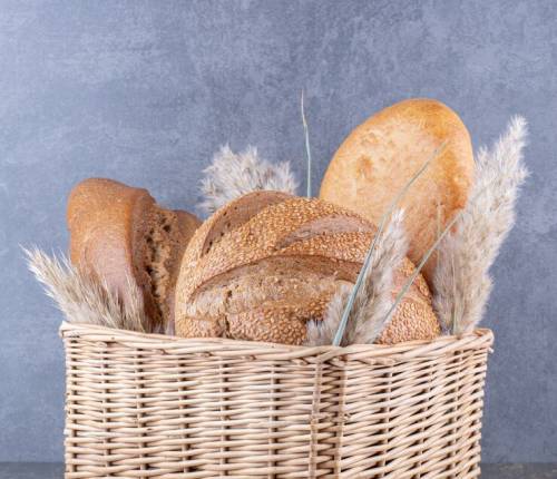 basket-filled-with-bread-loaves-feather-grass-stalks-marble-surface_114579-48039
