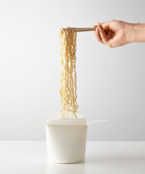 hand-picks-up-tasty-boiled-noodles-from-opened-wok-takeaway-blank-paper-box-isolated-white-center_346278-915