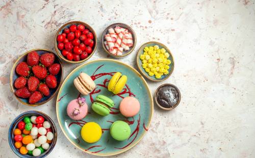 top-view-yummy-french-macarons-with-berries-candies-white-cake-sweet-biscuit_140725-124550